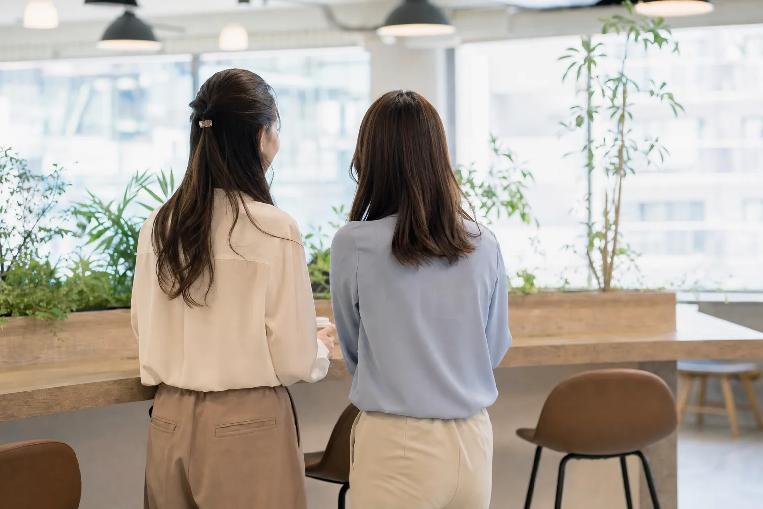 オフィスの休憩スペースで会話する二人の女性の後ろ姿