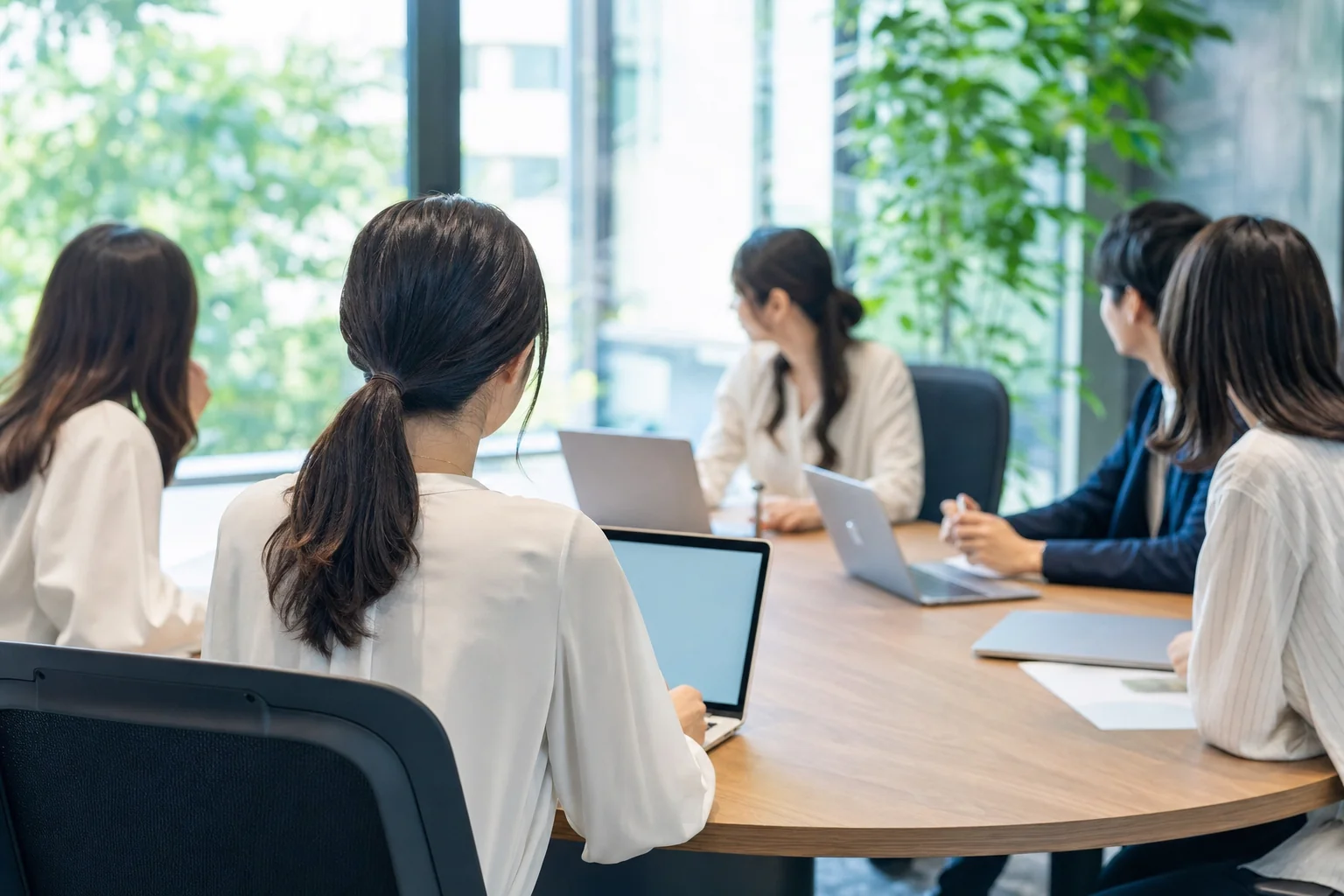 オフィスの会議室で、複数人が同席する場で業務の確認をしている日本の30代女性のイメージ写真